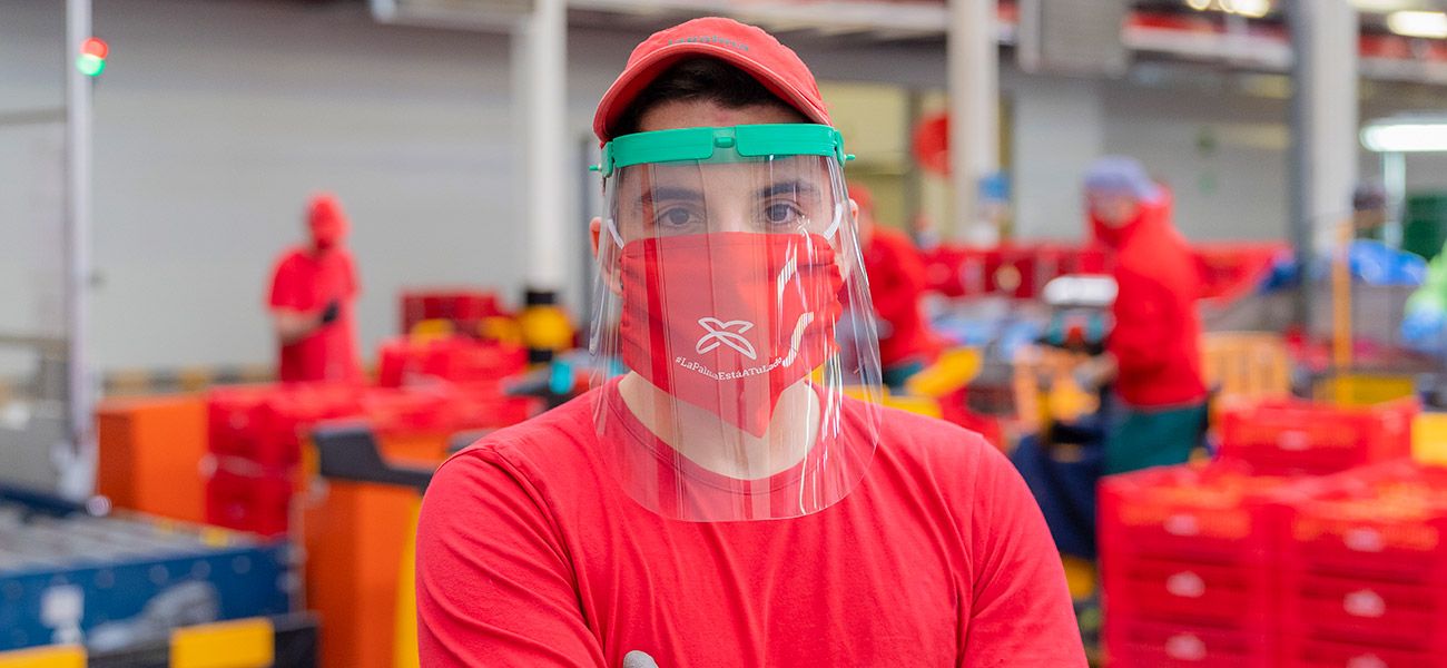 Trabajador de la cooperativa con mascarilla y pantalla de protección facial.